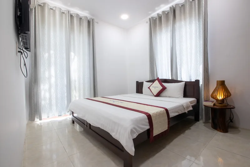White walls, tiled floor and a double bed in the Deluxe Garden View