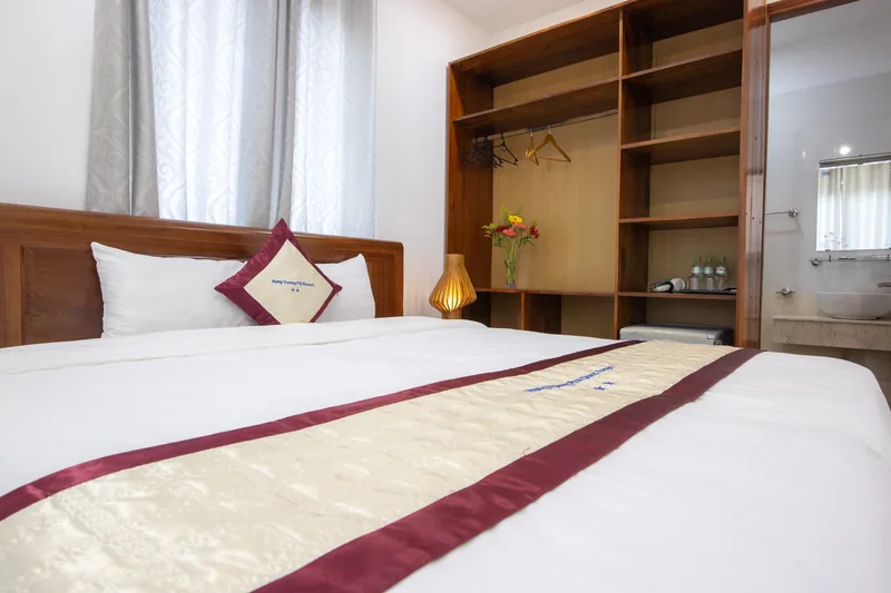 Bed and open wardrobe shelves in a Block A room