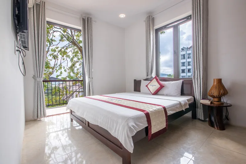 Deluxe Garden View room with a double bed and tall windows to the balcony