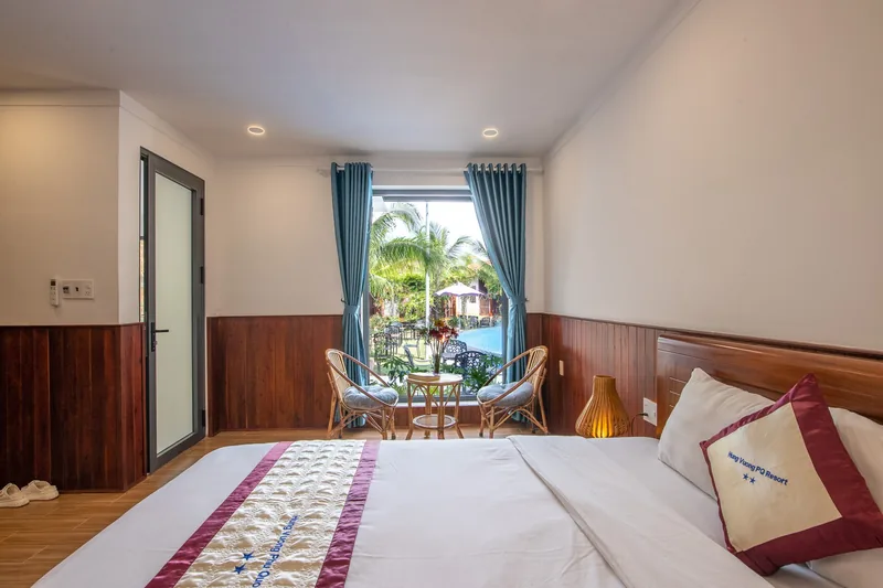 Bed and balcony door of a Deluxe Pool View room