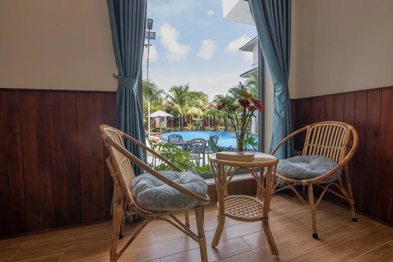 Rattan chairs by the window with the pool outside