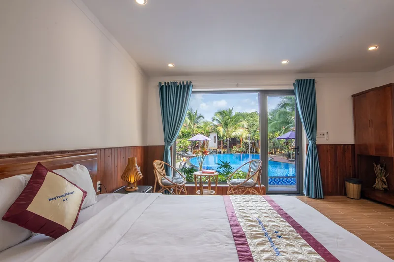 Deluxe Pool View room with the pool and palms seen through the open balcony door
