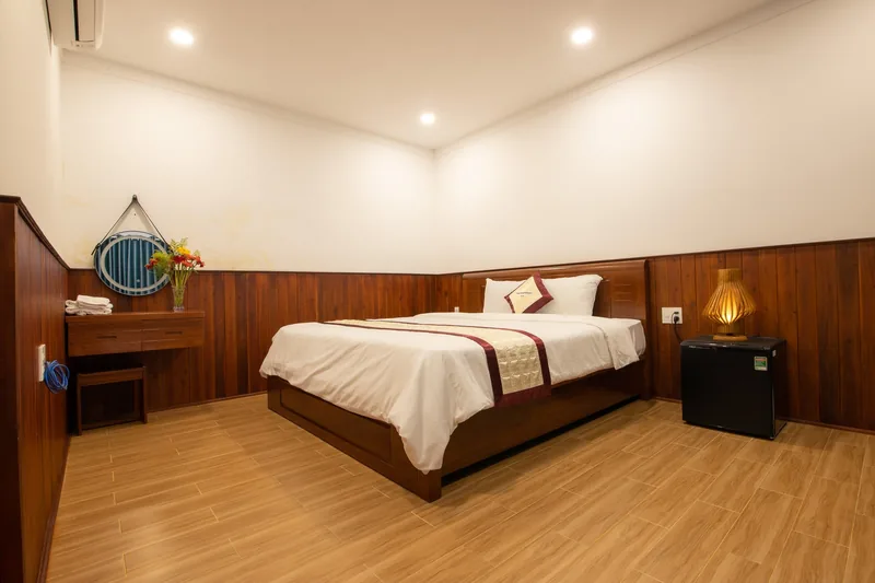 Double bed, rattan chairs and teal curtains in a Block C room