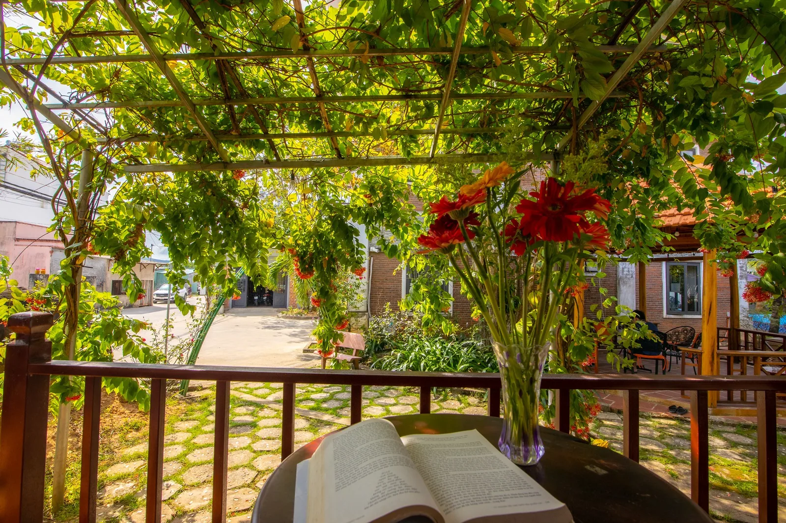 Vine-covered terrace of the Family Bungalow with flowers and a table in the garden