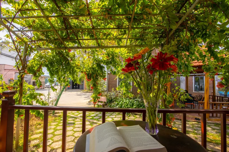 Vine-covered terrace of the Family Bungalow with flowers and a table in the garden