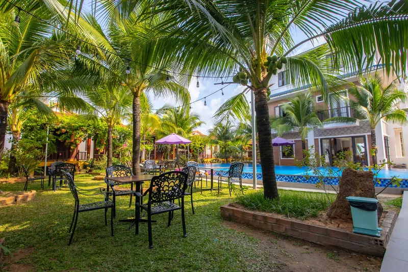 Garden tables under coconut palms beside the pool