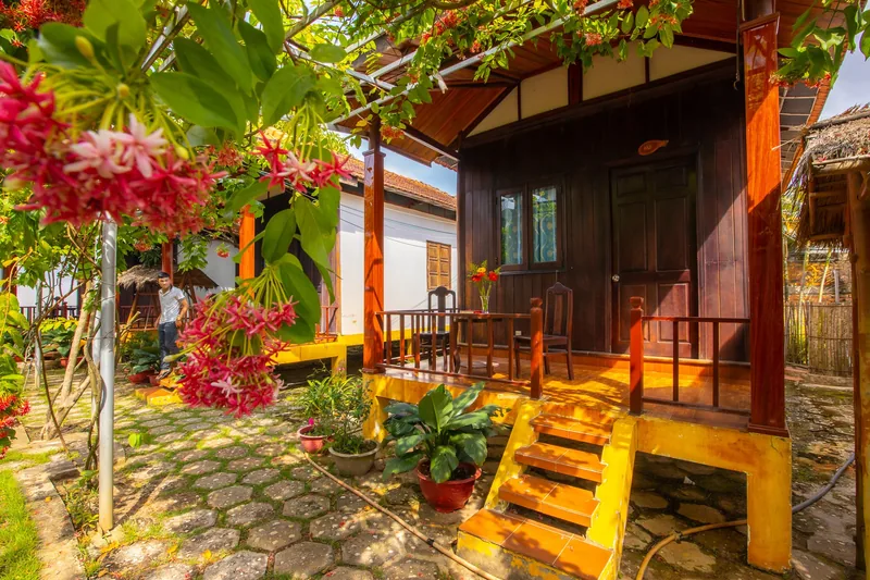 Front of a Garden View Bungalow with wooden steps and red flowers