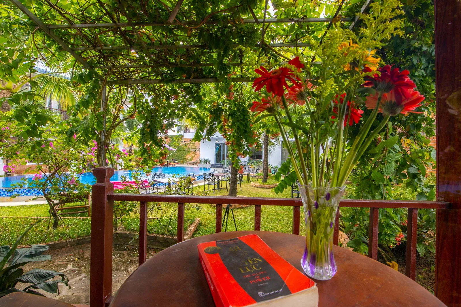 Terrace of a Pool View Bungalow with flowers and the pool beyond the garden