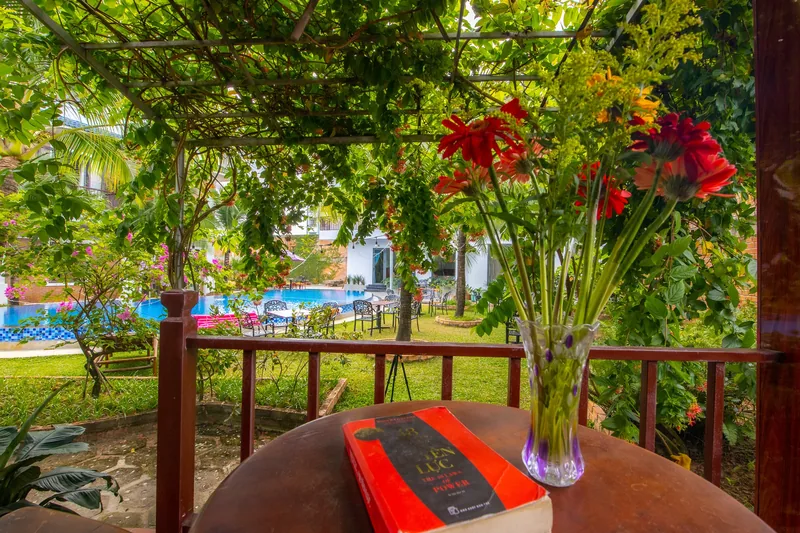 Terrace of a Pool View Bungalow with flowers and the pool beyond the garden