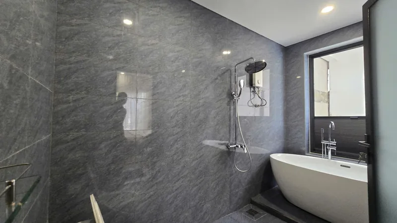 Freestanding bathtub and rain shower in grey stone
