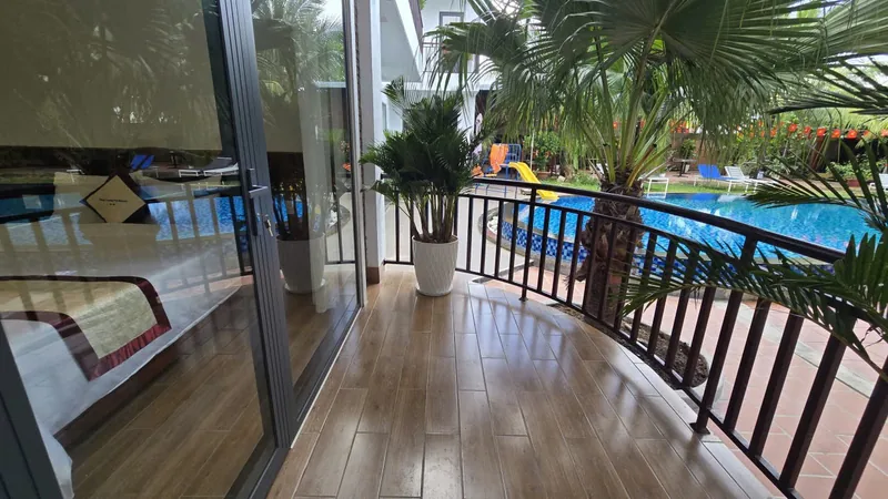 Curved balcony of a Premium Pool View room above the pool and palms